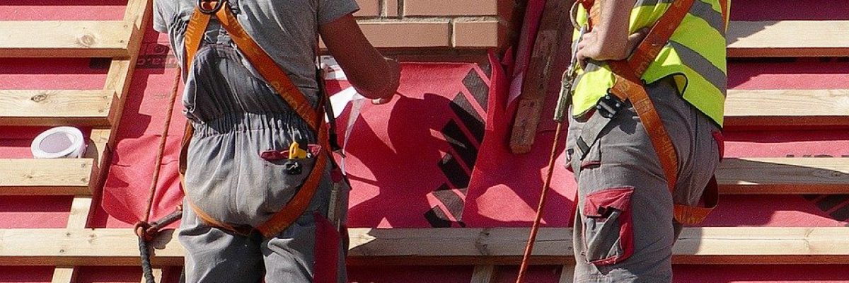 Two handyman working on a roof with a red tarp.