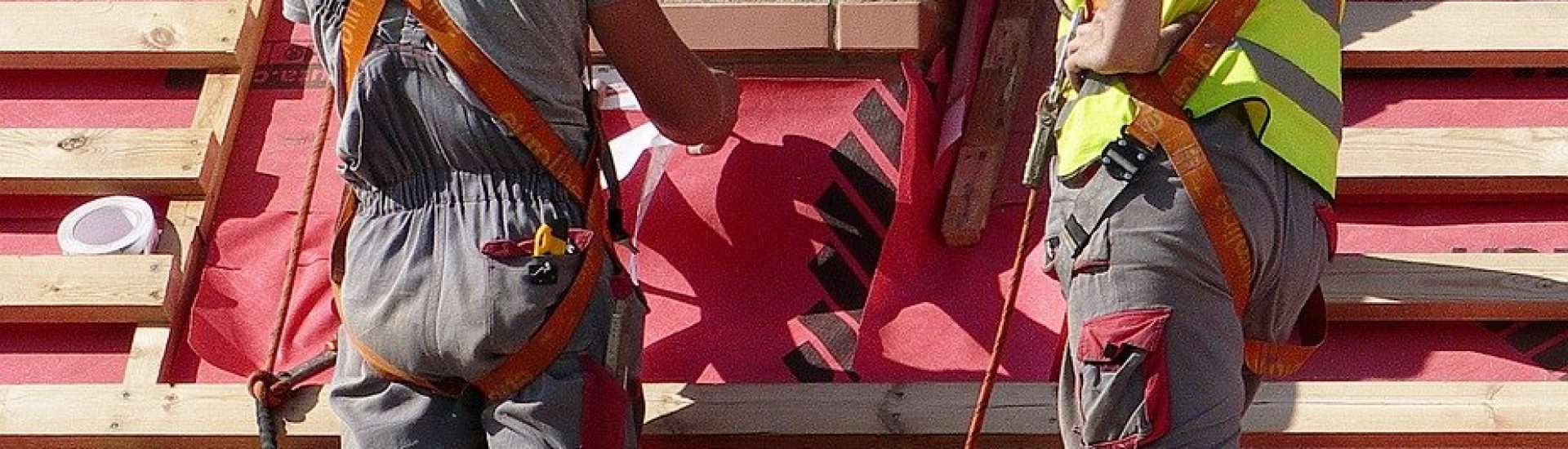 Two handyman working on a roof with a red tarp.